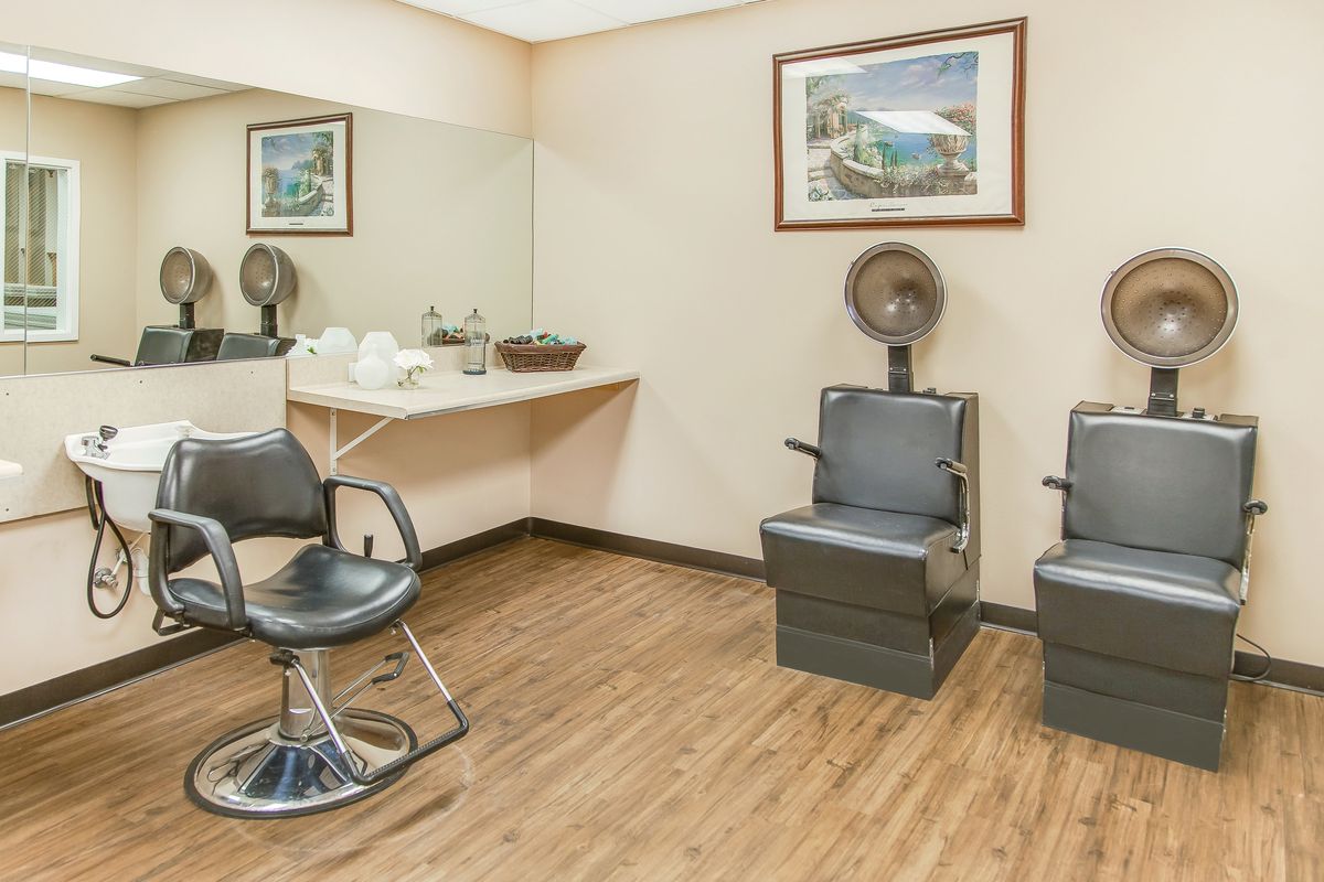 A salon interior with hair styling chairs and a wall-mounted mirror.