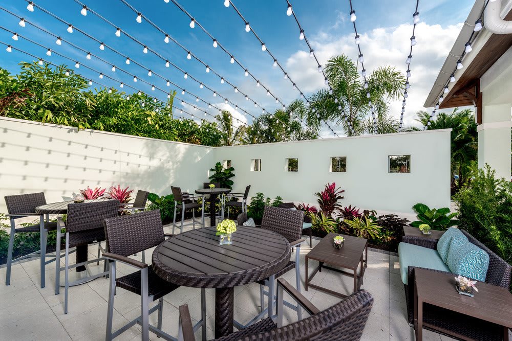 An inviting outdoor patio with seating and string lights under a clear sky.