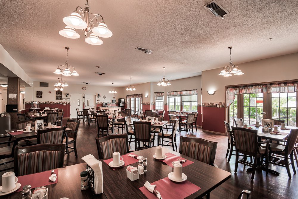 A spacious restaurant dining area with neatly arranged tables and chairs, soft lighting, and a warm atmosphere.