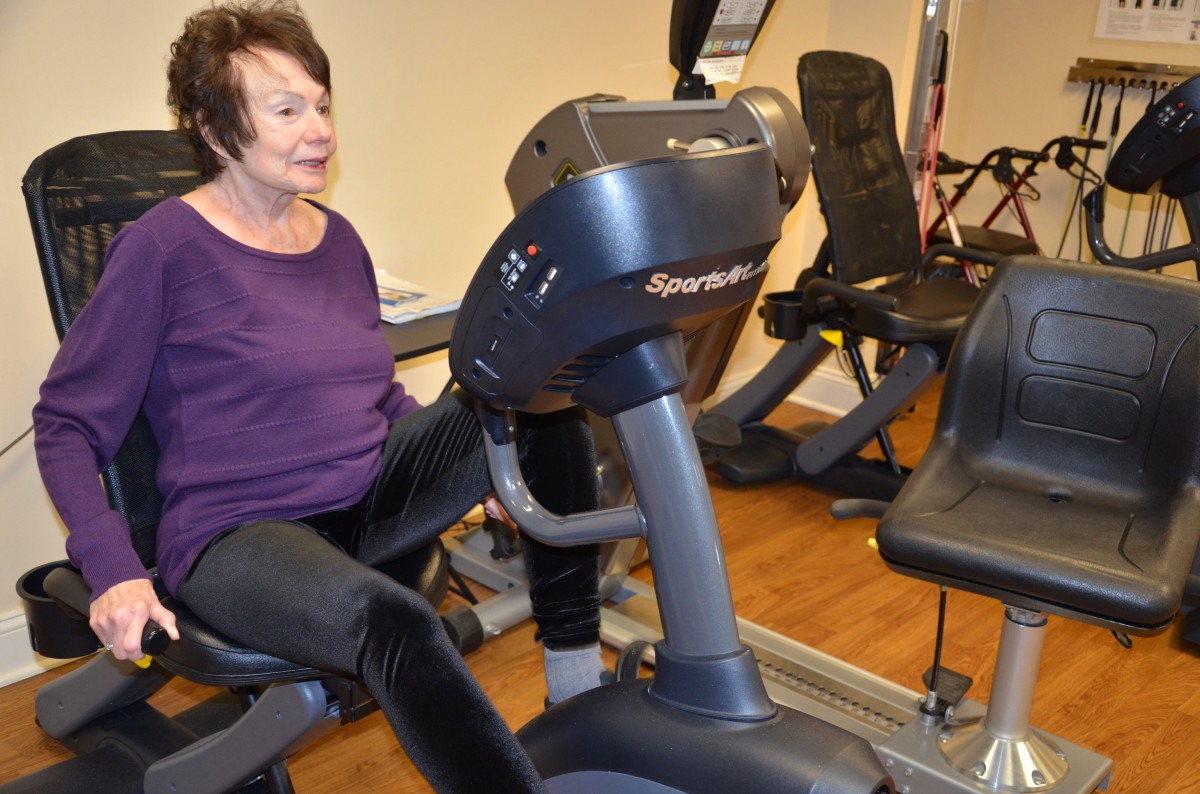 A woman exercising on a recumbent bike at the gym.