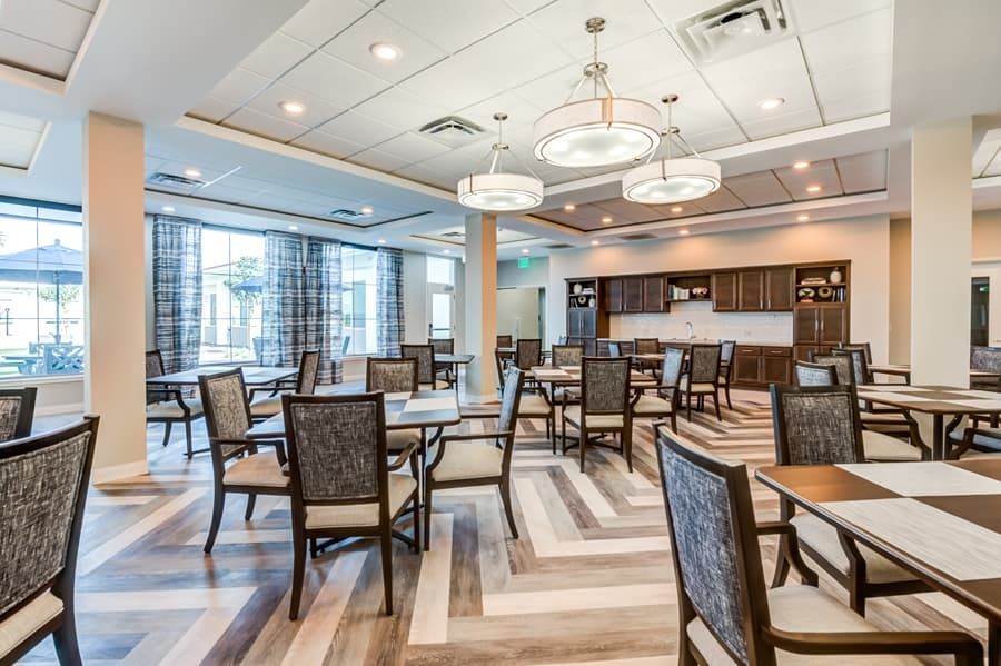 A modern dining area with neatly arranged tables and chairs, featuring stylish lighting and wood flooring.