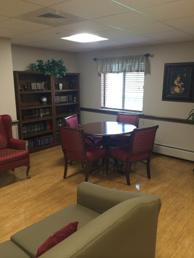 A cozy indoor space featuring a table and chairs, complemented by bookshelves and natural light.
