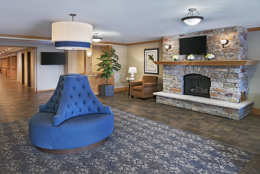 A cozy hotel lobby with a central blue seating area, fireplace, and elegant decor.