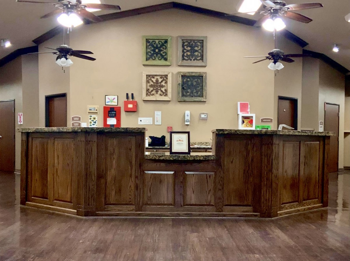 A reception area with a wooden desk and decorative artwork on the wall.