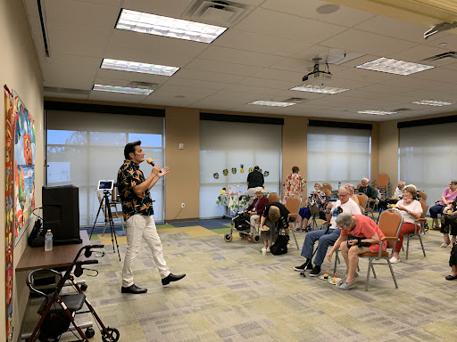 A performer engages with an audience at a community center event.