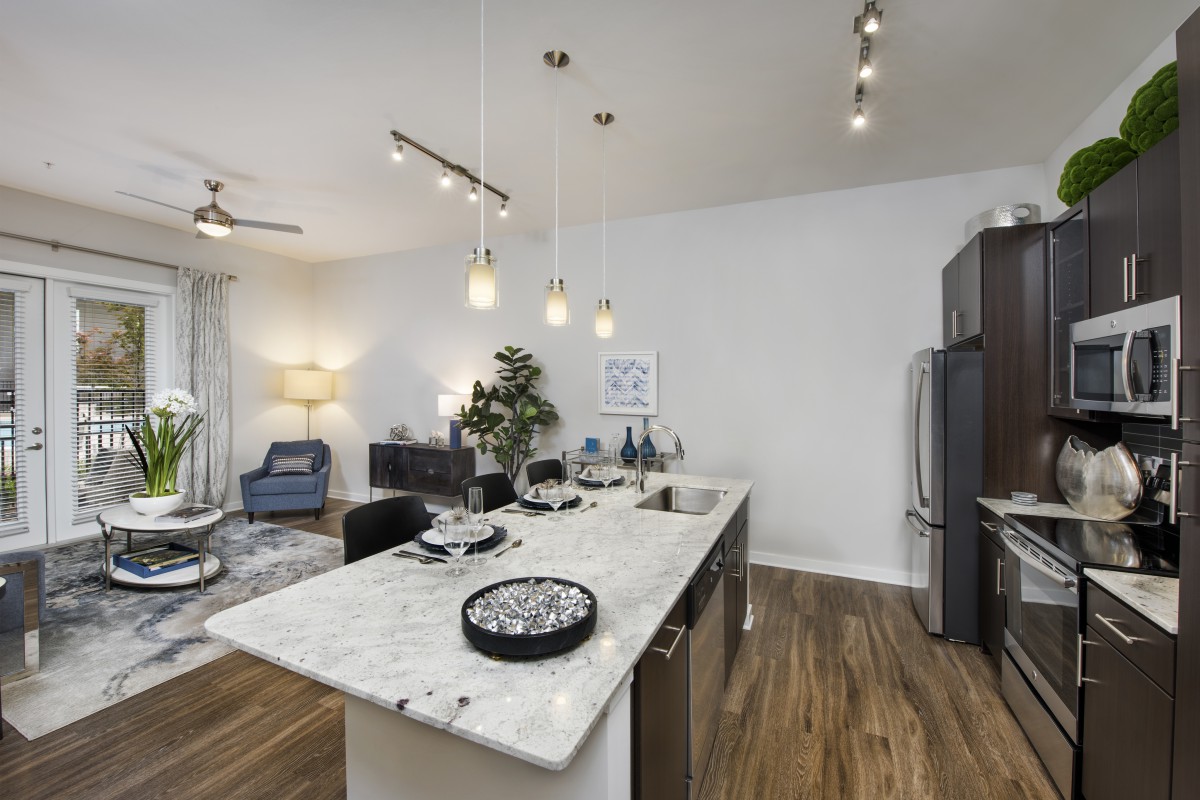 A modern open-concept kitchen and living area with stylish pendant lights and a central island.