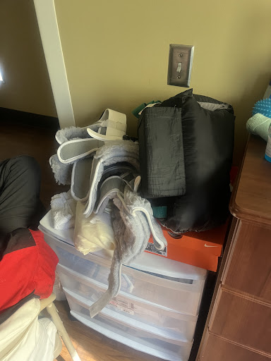 A cluttered corner showing a pile of clothes and bags on top of storage drawers.