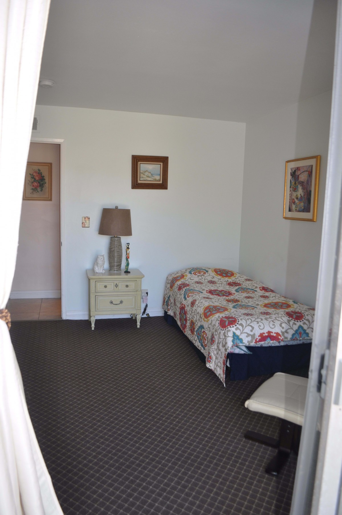 A cozy bedroom with a single bed, side table, and decorative artwork.