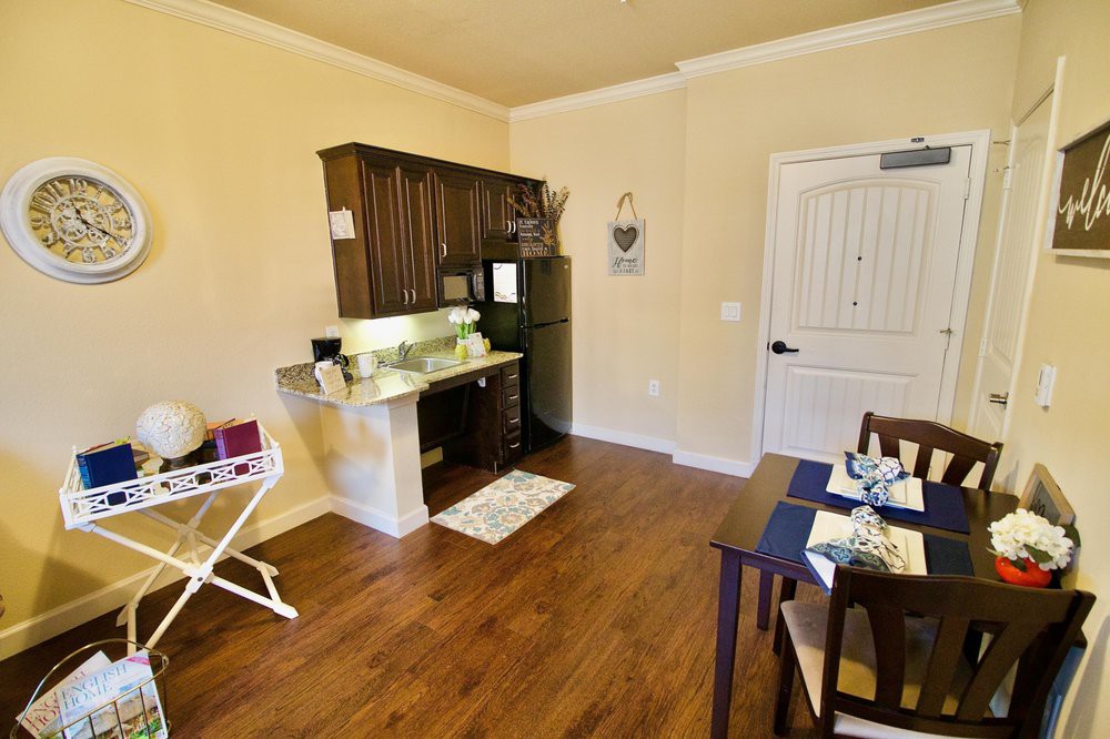 A cozy apartment with a compact kitchen and dining area, featuring wooden floors.