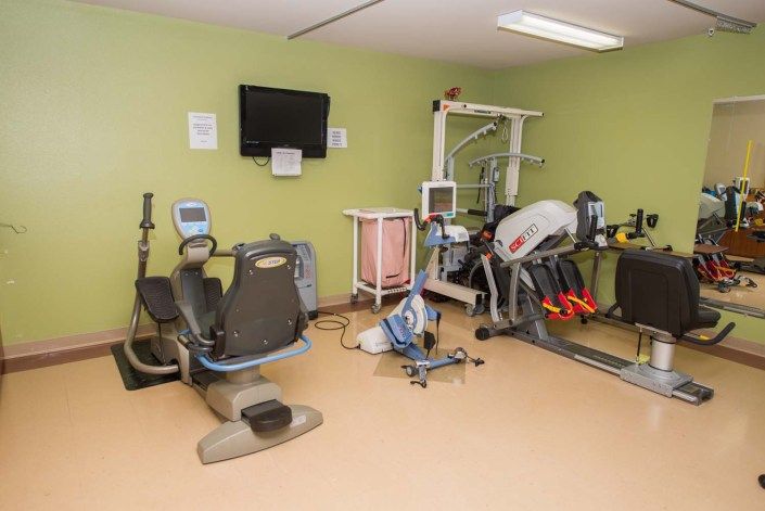 A small exercise room with various fitness equipment, including stationary bikes and a treadmill.