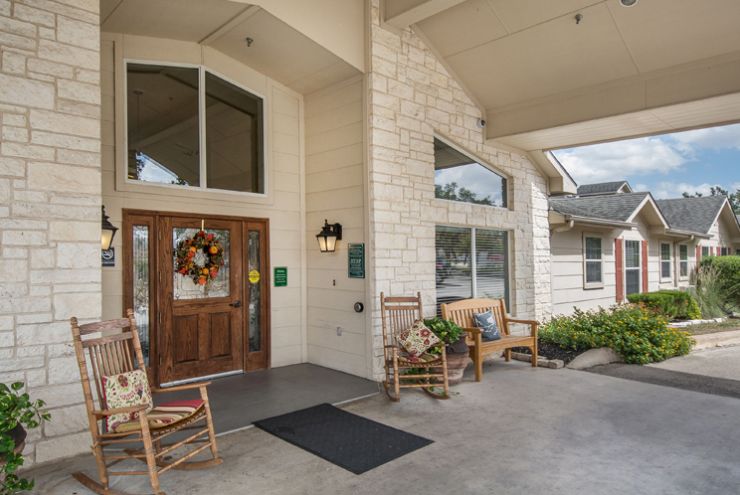 A welcoming building entrance with rocking chairs and seasonal decorations.