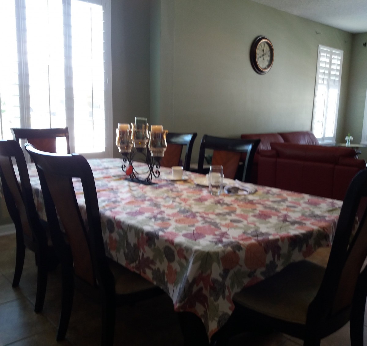 A cozy dining room featuring a table with a floral tablecloth and candle centerpiece.
