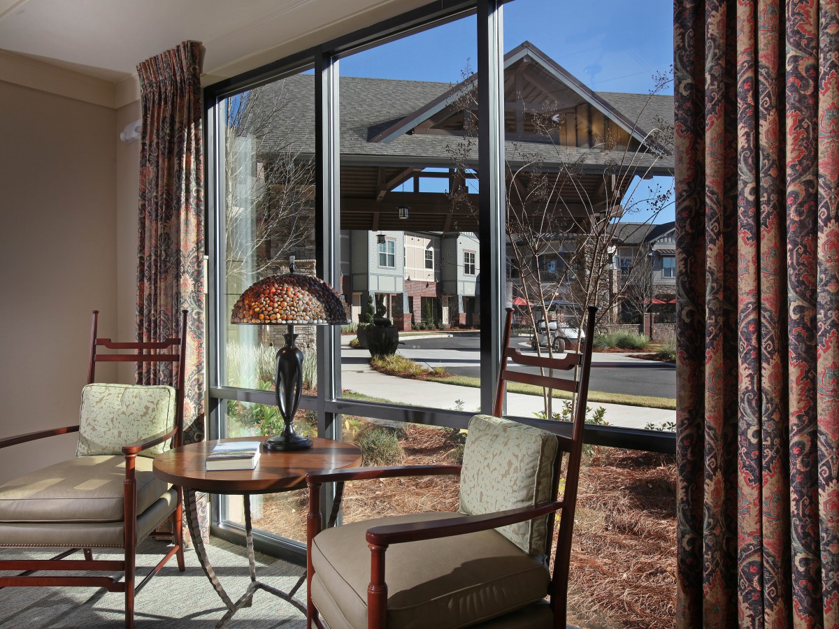 A cozy interior space with two chairs and a table by a large window overlooking outdoor architecture.