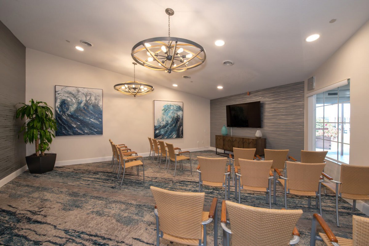 A modern conference room with seating arranged in rows, featuring elegant chandeliers and contemporary artwork on the walls.
