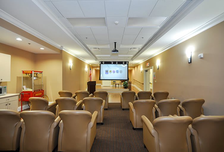 A cozy home theater room with several comfortable chairs facing a large screen.