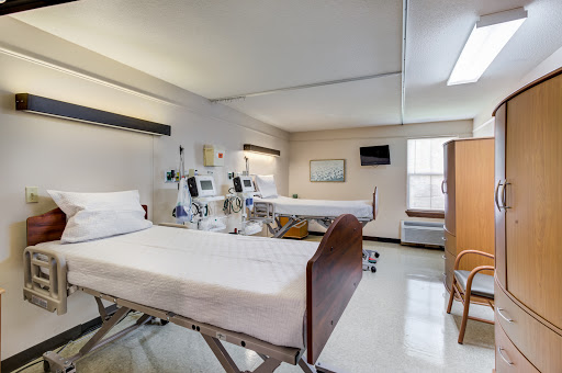 A clean and well-lit hospital room equipped with two adjustable beds and medical equipment.