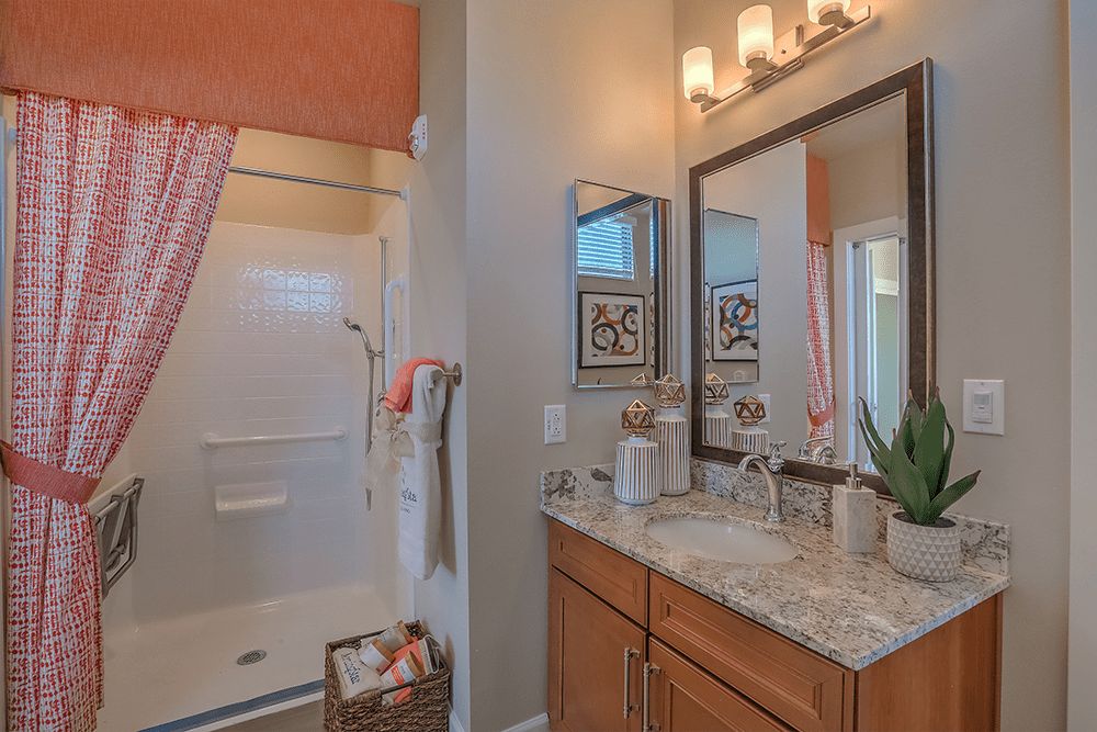 A well-lit bathroom with a modern vanity and shower area, decorated with towels and plants.