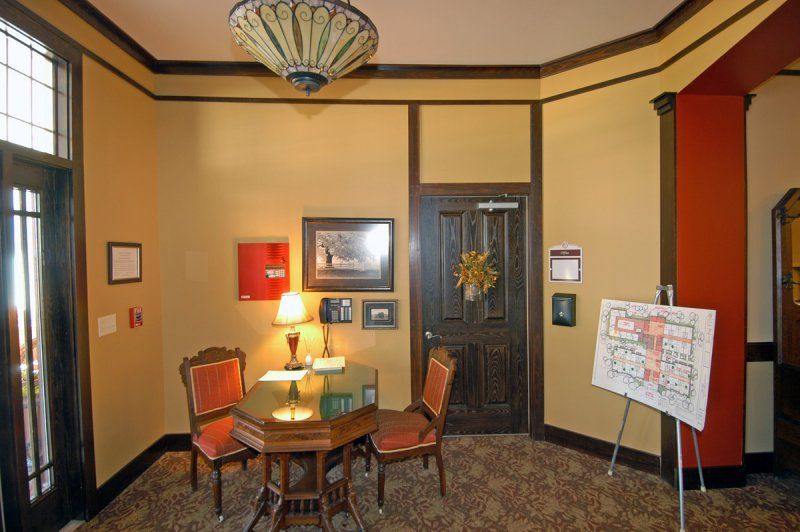 A cozy room with a small round table, chairs, wall decorations, and a lamp.