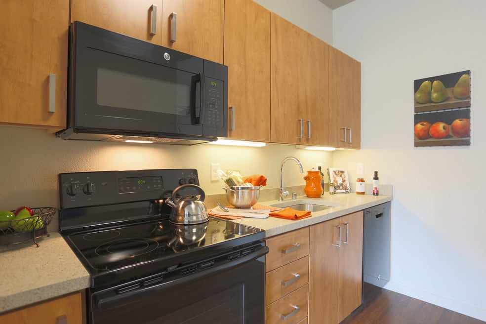 A modern kitchen with wooden cabinets and black appliances.
