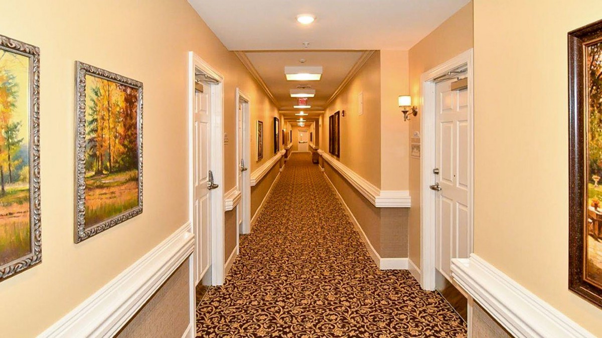A well-lit hotel hallway with patterned carpet and multiple doors.