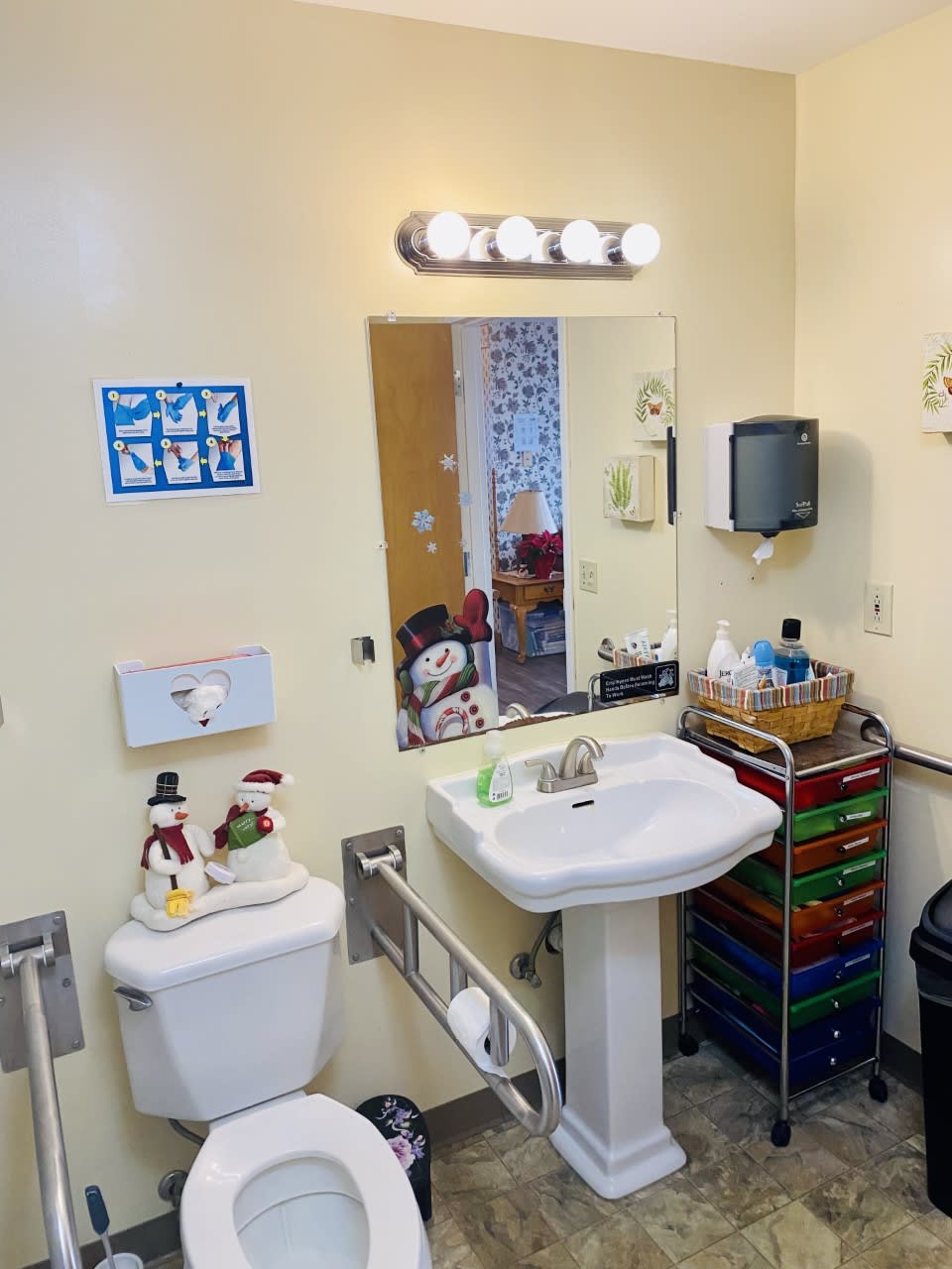 A well-equipped and decorated bathroom with a mirror, sink, toilet, and storage cart.
