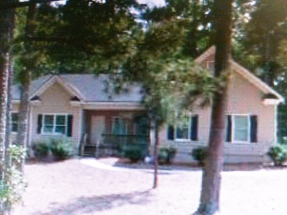 A suburban house surrounded by trees with a small front yard.