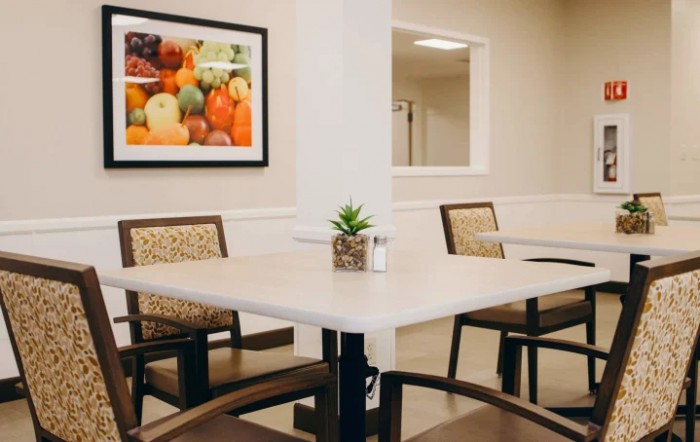 A cozy dining area featuring a table with chairs and a small potted plant, complemented by wall art depicting fruits.
