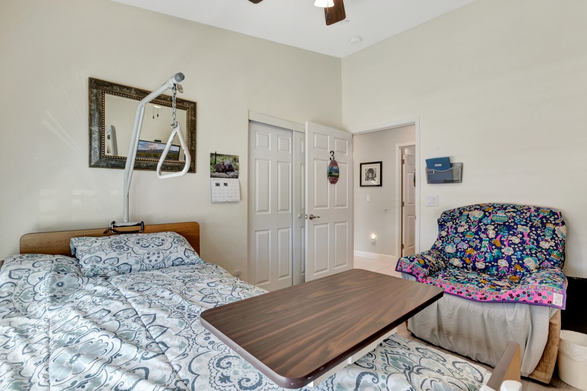 A cozy bedroom with a hospital bed, ceiling fan, and decorative artwork.