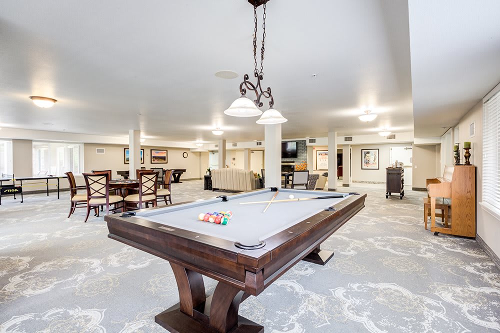 Spacious game room with a central pool table and elegant furnishings.
