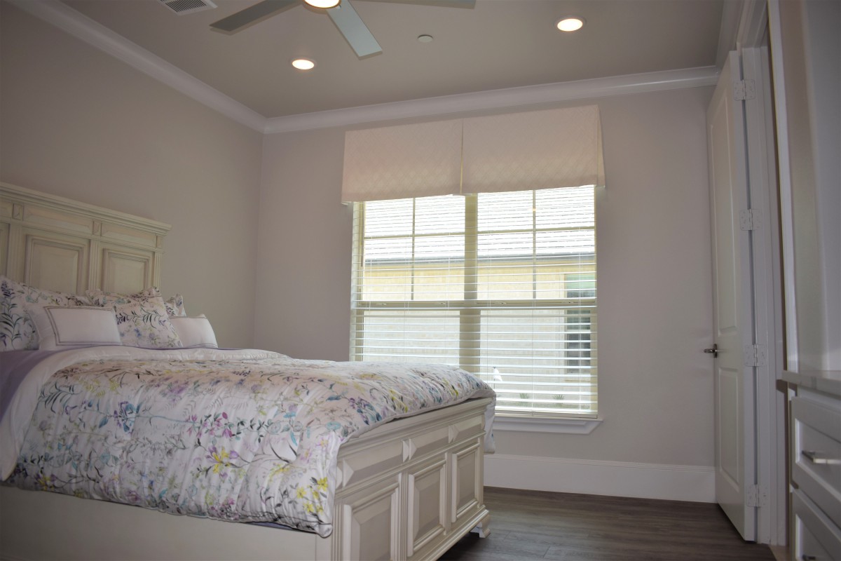 A cozy bedroom with a bed, window blinds, and a ceiling fan.