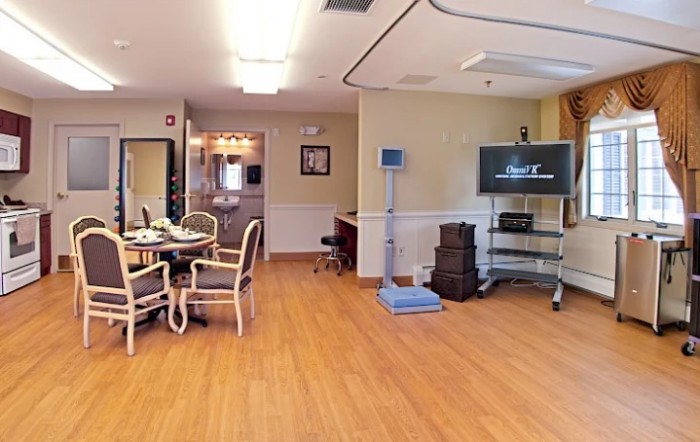 A cozy living room interior with a TV, chairs, and a wooden floor.