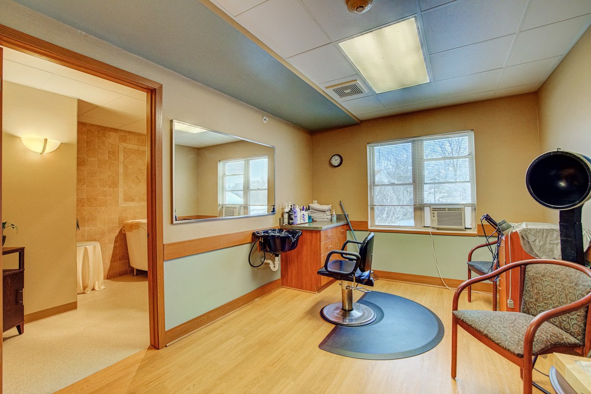 A brightly lit salon interior featuring a barber chair and mirror.