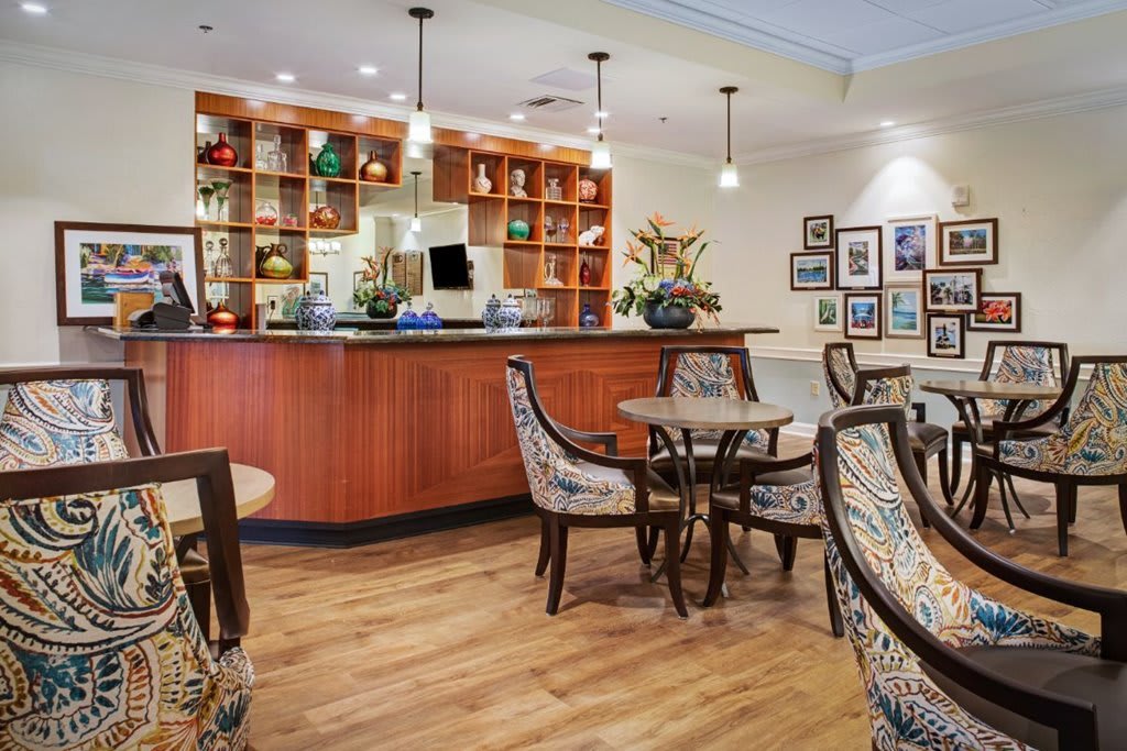 A cozy cafe interior featuring a wooden bar counter, stylish chairs, and decorative artwork on the walls.