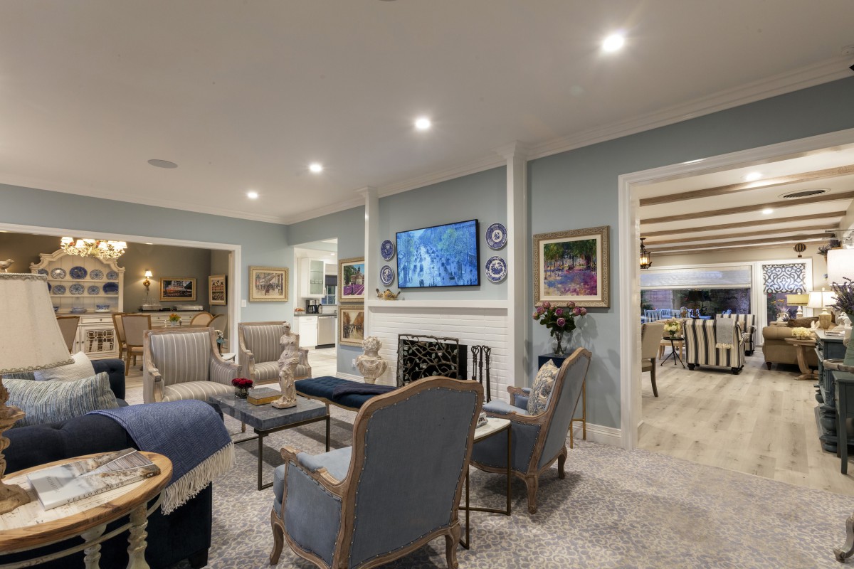 A cozy and elegantly designed living room with a central fireplace, television, and comfortable seating area.