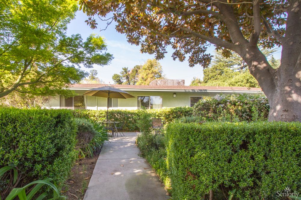 A charming house with a well-maintained garden pathway surrounded by lush greenery.