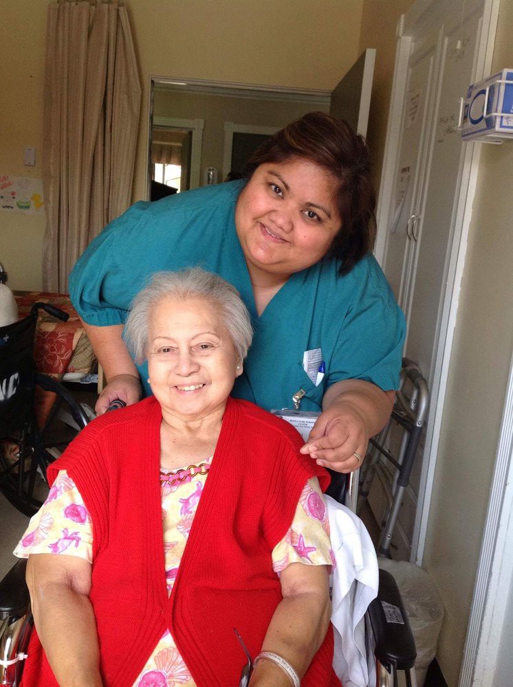 A caregiver and an elderly woman smiling together at home.