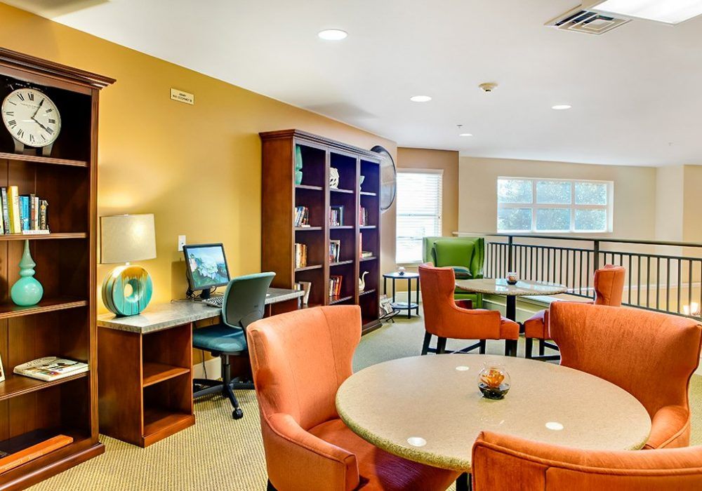 A cozy lounge area with tables, chairs, and a computer workstation.