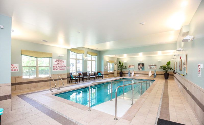 An inviting indoor swimming pool with surrounding seating in a well-lit recreational area.