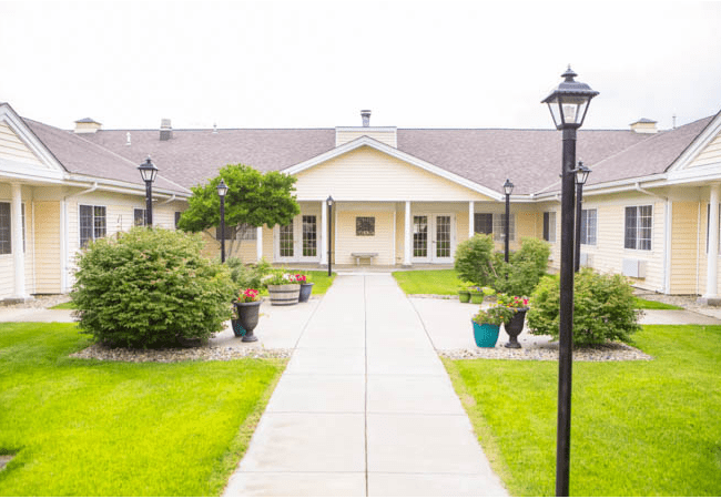 A landscaped pathway leading to a residential building with outdoor lighting.