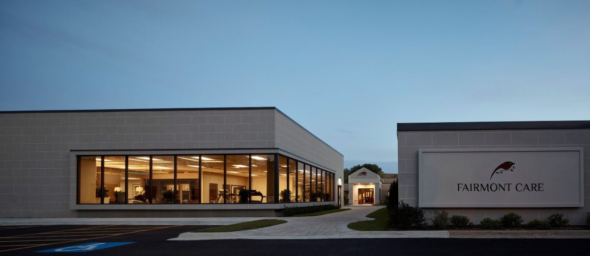 A modern building with large windows illuminated in the evening light.