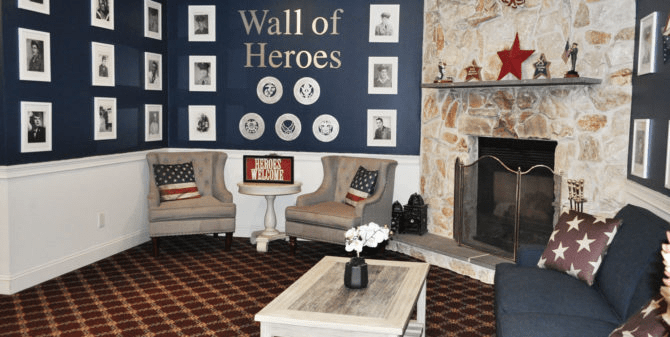 A cozy seating area with a 'Wall of Heroes' displaying portraits, complemented by patriotic decor and a warm fireplace.