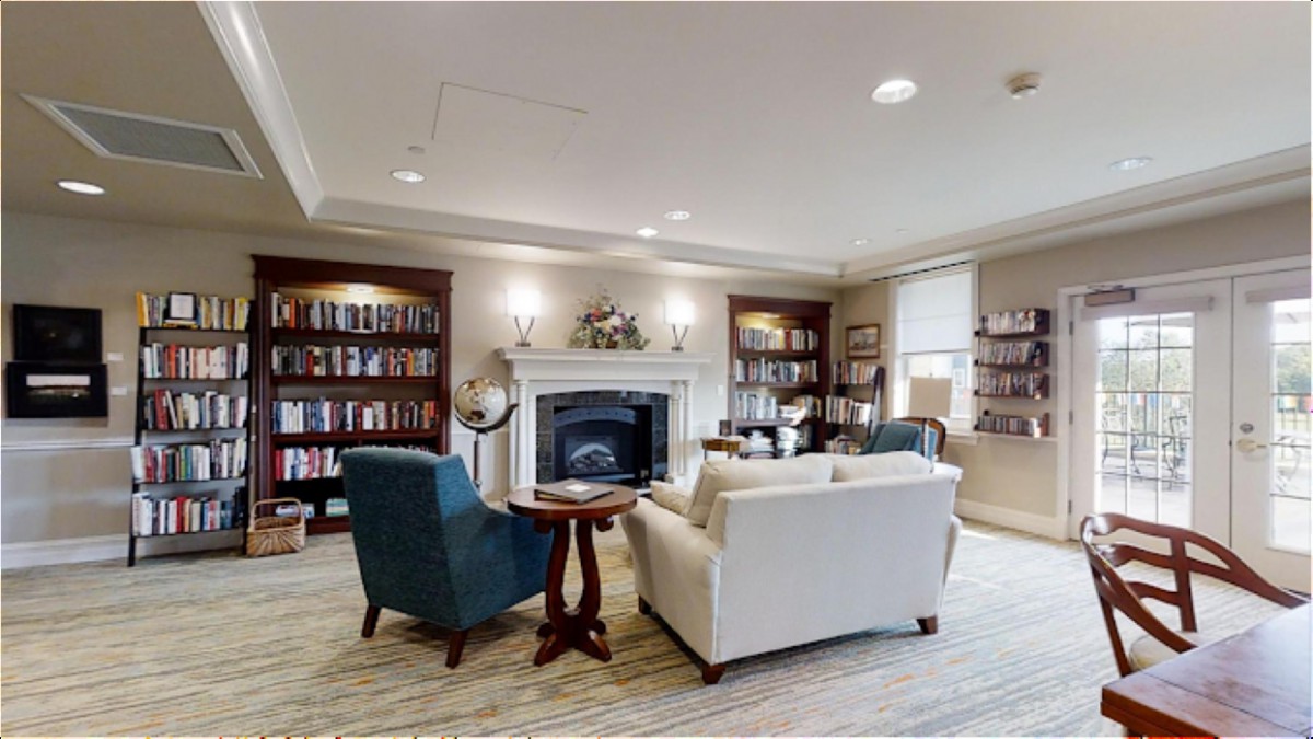A cozy library space with bookshelves, a fireplace, and comfortable seating.