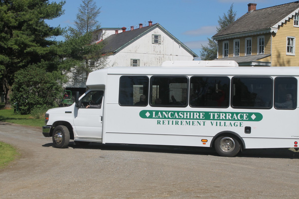 A shuttle bus parked outside a building, labeled 'Lancashire Terrace Retirement Village'.