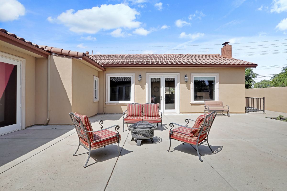 A sunny backyard patio with outdoor furniture and a fire pit.