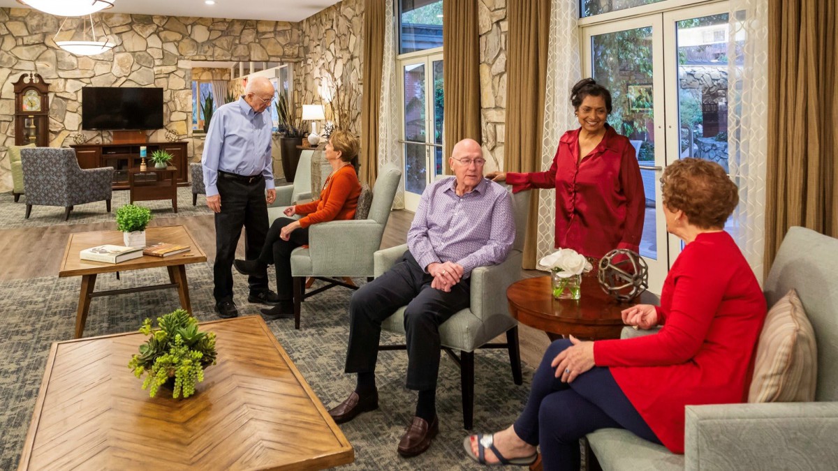 A group of seniors enjoying a conversation in a cozy living room setting at a retirement home.