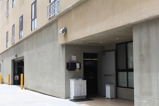 The entrance of a modern building featuring a concrete facade and a security camera.