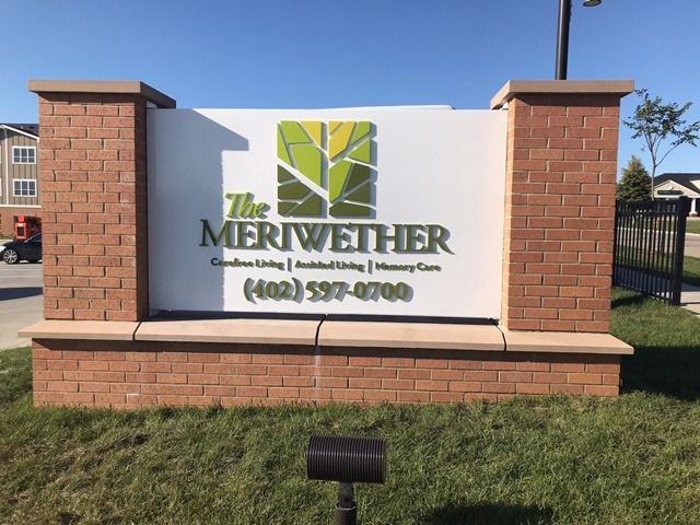 A sign on a brick structure advertising 'The Meriwether' with contact information.