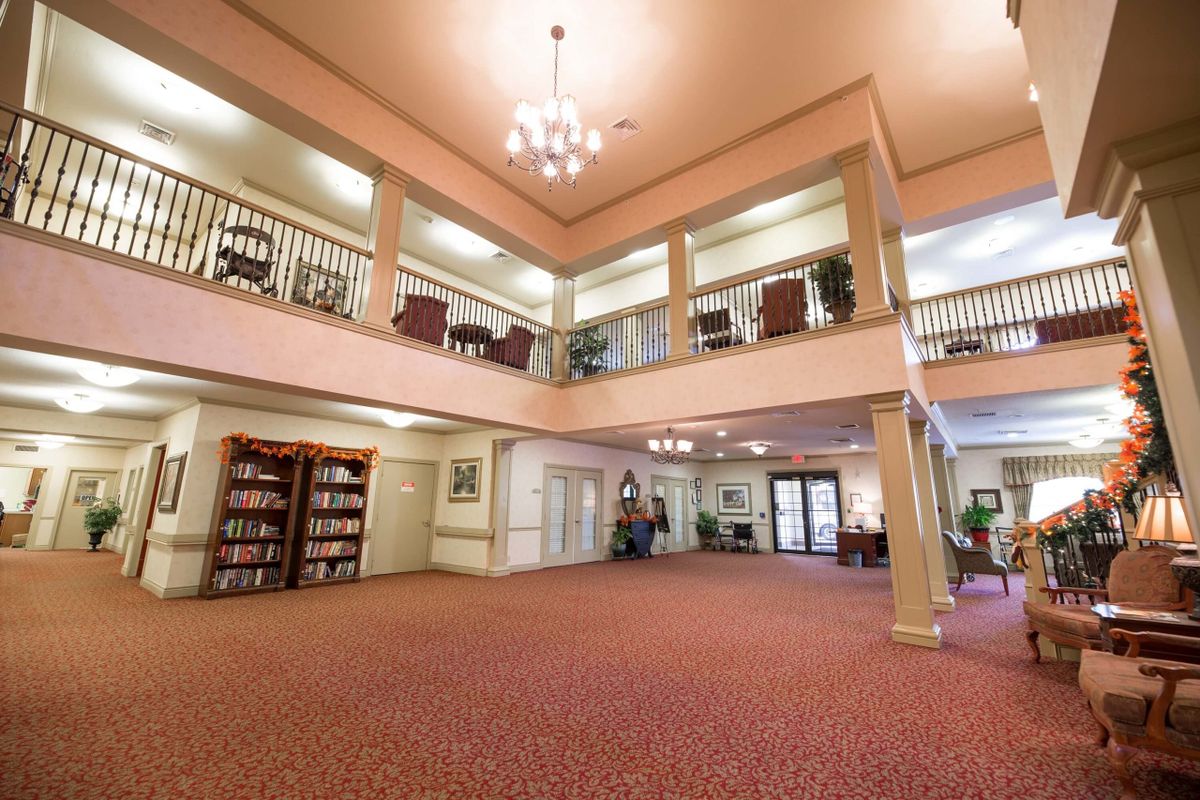 A spacious lobby with high ceilings, a chandelier, balconies, and a small library area.