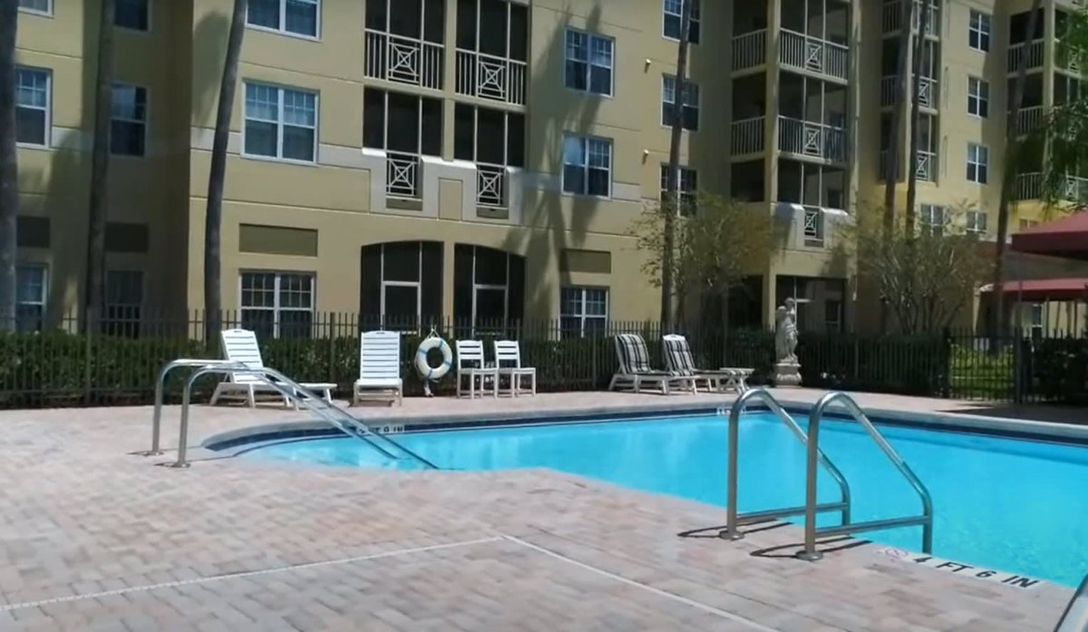 A sunny day at an apartment complex with a swimming pool and lounge chairs.