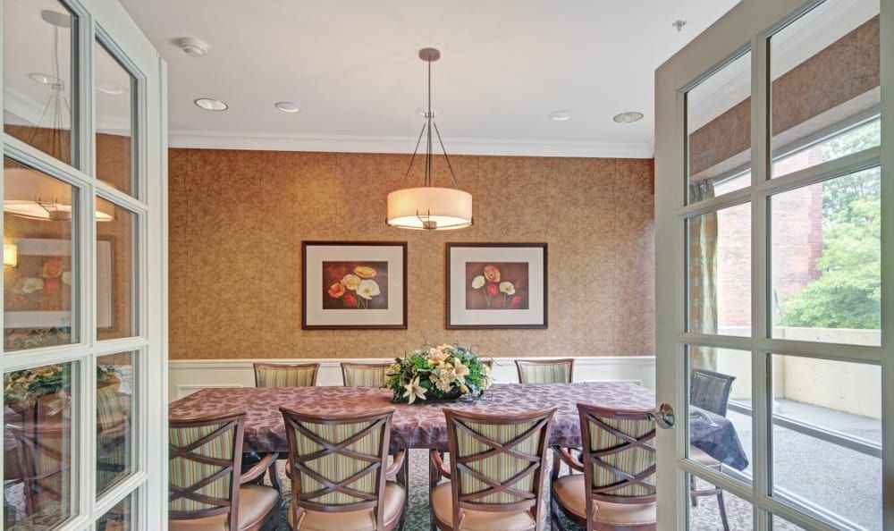 A dining room with a long table and several chairs, featuring a chandelier and framed wall art.